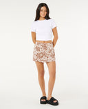 Woman wearing a white crop top and floral skort on a white background