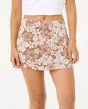 Woman wearing a white crop top and floral skort on a white background