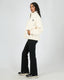 Model wearing All About Eve Amara Quarter Zip Teddy in vintage white, showing side view with hands in front pockets