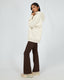 Model wearing All About Eve Elements oversized hoodie in oat color with brown flared pants and sneakers against grey background