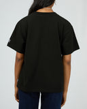 Back view of All About Eve Basic Monogram Tee in black showing relaxed fit and short sleeves against white background