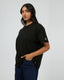 All About Eve Basic Monogram Tee in black cotton, relaxed fit with sleeve logo detail against grey background