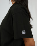 All About Eve black monogram tee with relaxed fit and white EVE logo on sleeve, shown from side angle