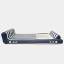 An inflatable lounge bed by SUNNYLIFE, featuring navy blue and cream stripes with a solid navy blue base and headrest, shown on a light gray background.