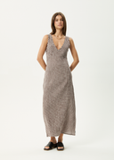 A model wearing a sleeveless, v-neck, maxi dress with a coffee check pattern, standing against a white background. afends checkered brown dress coffee